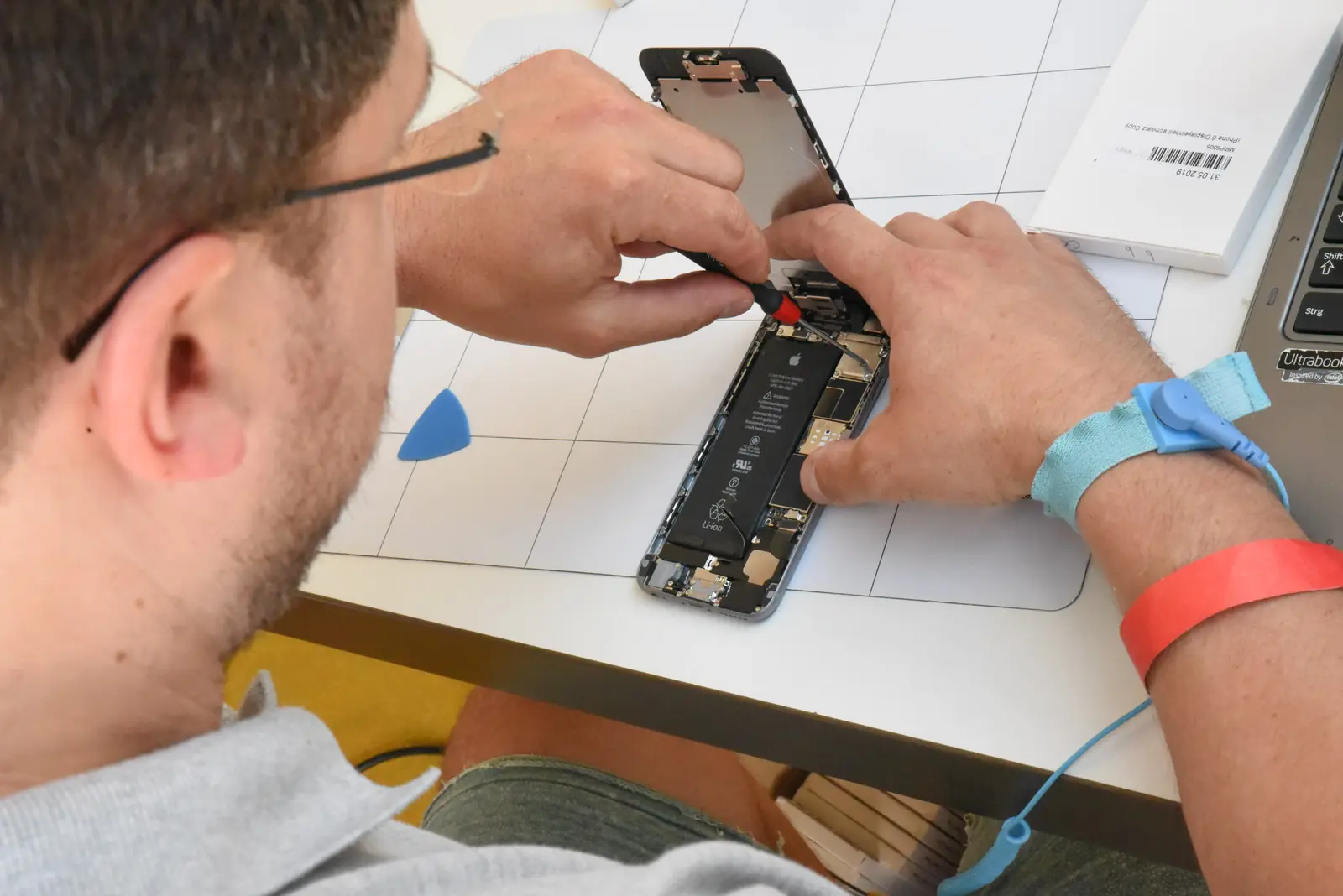 Un réparateur ouvre un smartphone sur son établi